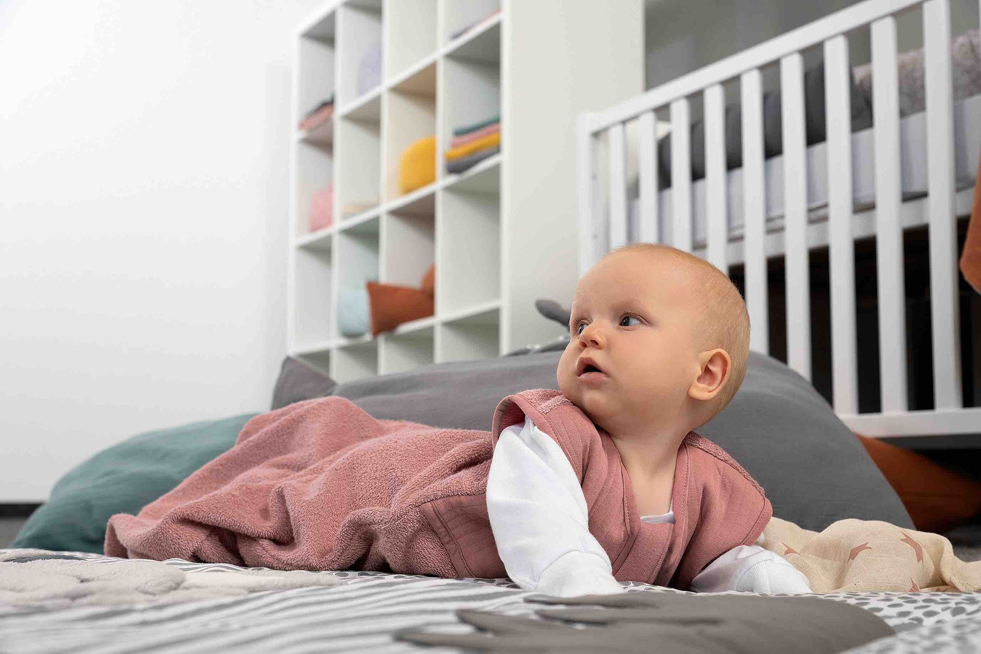 Frottee Schlafsack mit Baby im Kinderzimmer auf dem Boden