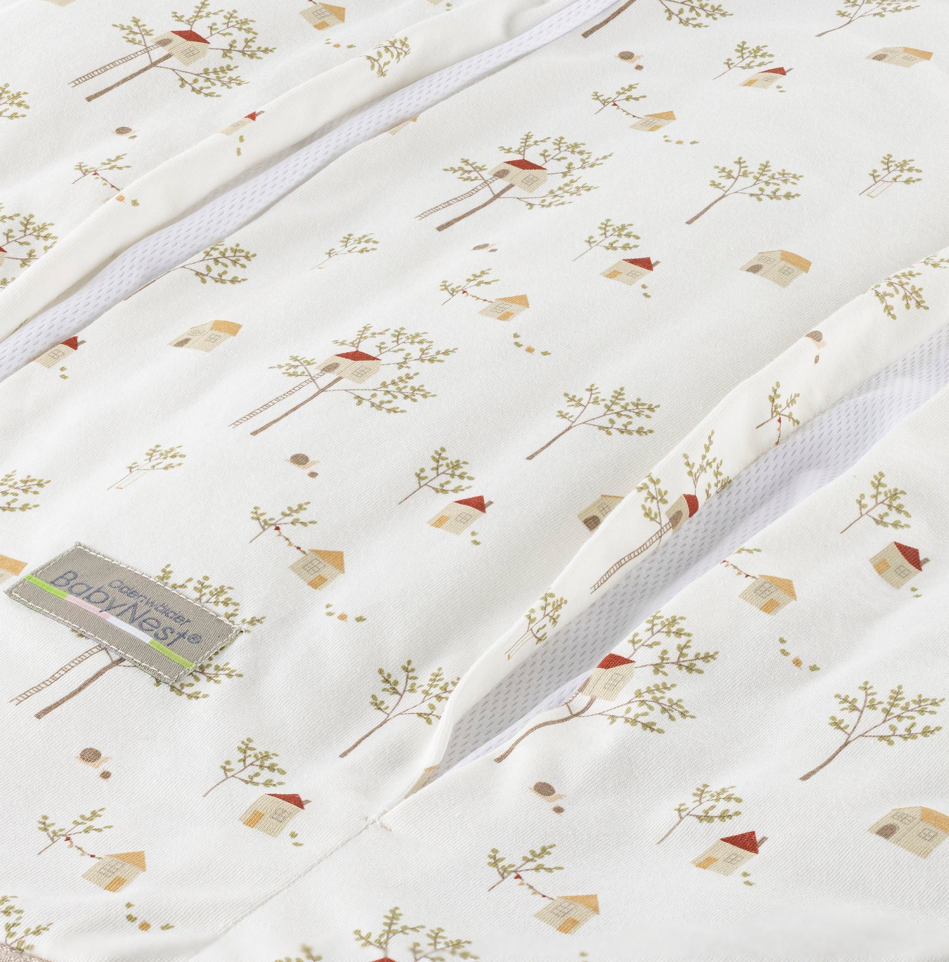 Detailaufnahme des prima klima Jersey‑Schlafsacks für Babys in der Designvariante Treehouse mit mehreren Baumhaus-Muster auf hellem Stoff und sichtbarer Reißverschlussöffnung samt Jersey‑Materialstruktur, freigestellt dargestellt.