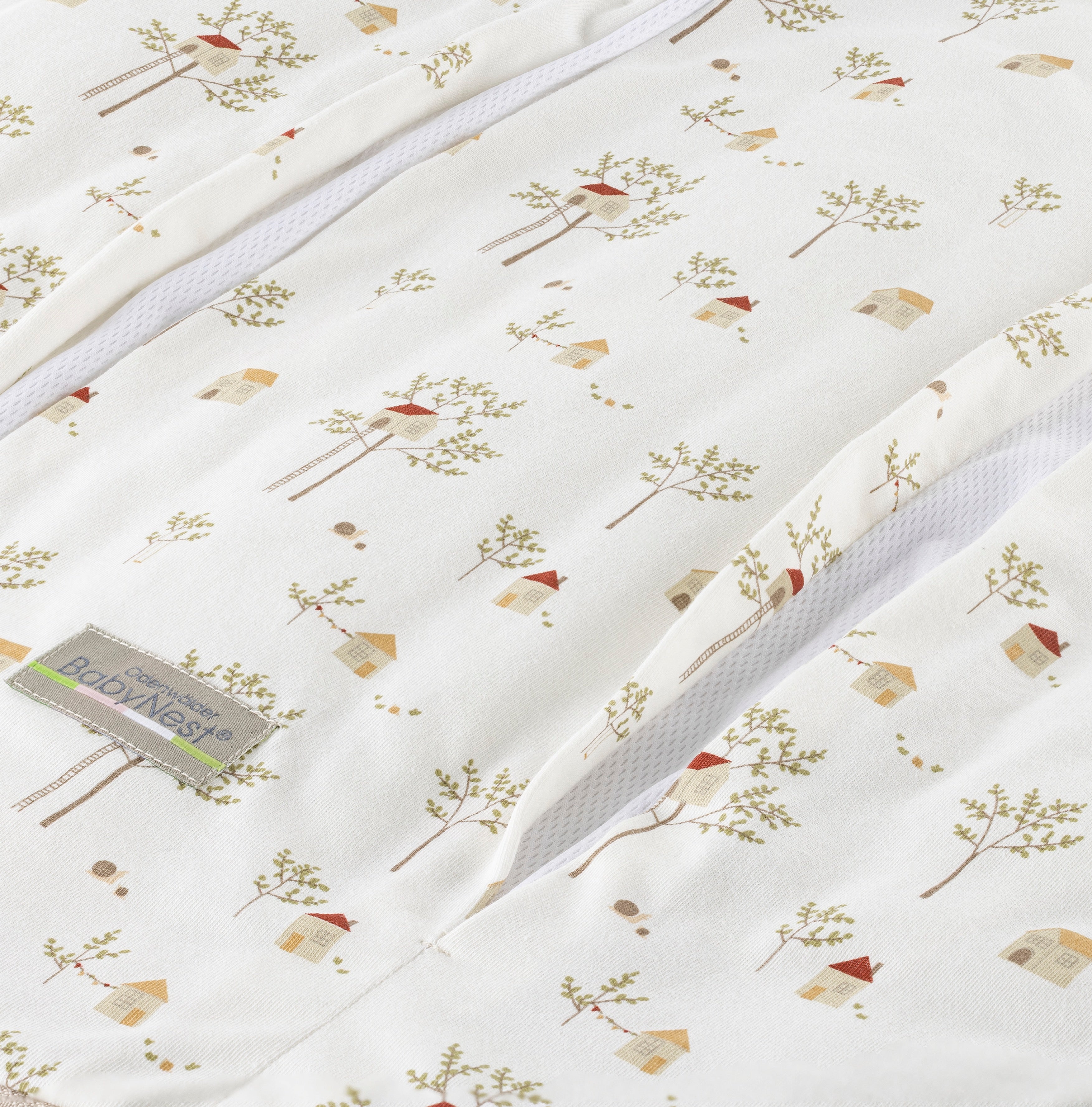 Detailaufnahme des prima klima Jersey‑Schlafsacks für Babys in der Designvariante Treehouse mit mehreren Baumhaus-Muster auf hellem Stoff und sichtbarer Reißverschlussöffnung samt Jersey‑Materialstruktur, freigestellt dargestellt.