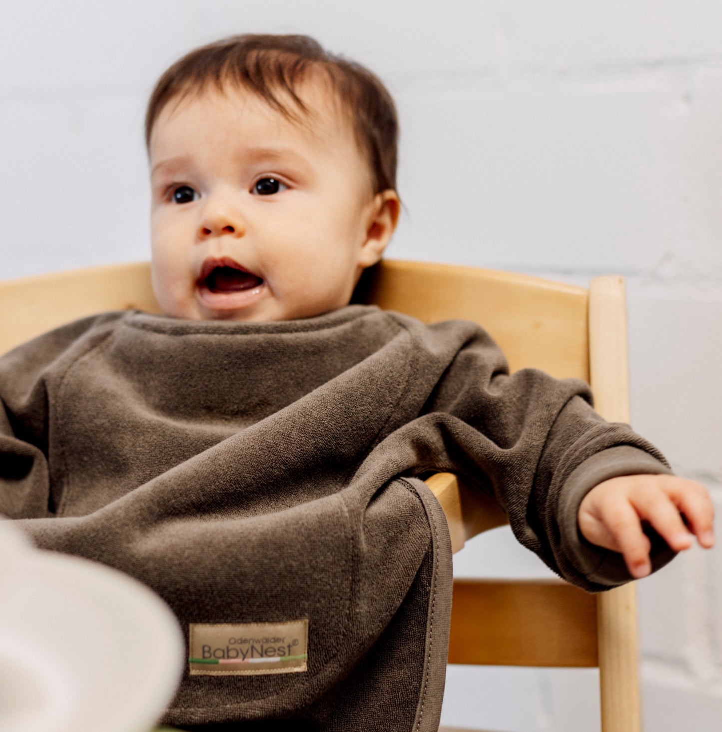 Beikost Bundle, Baby sitzt im Hochstuhl und trägt ein Baby Ärmellätzchen wasserdicht